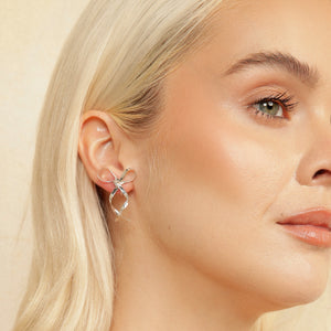 Close up of blonde model wearing mini silver bow clip-on earrings