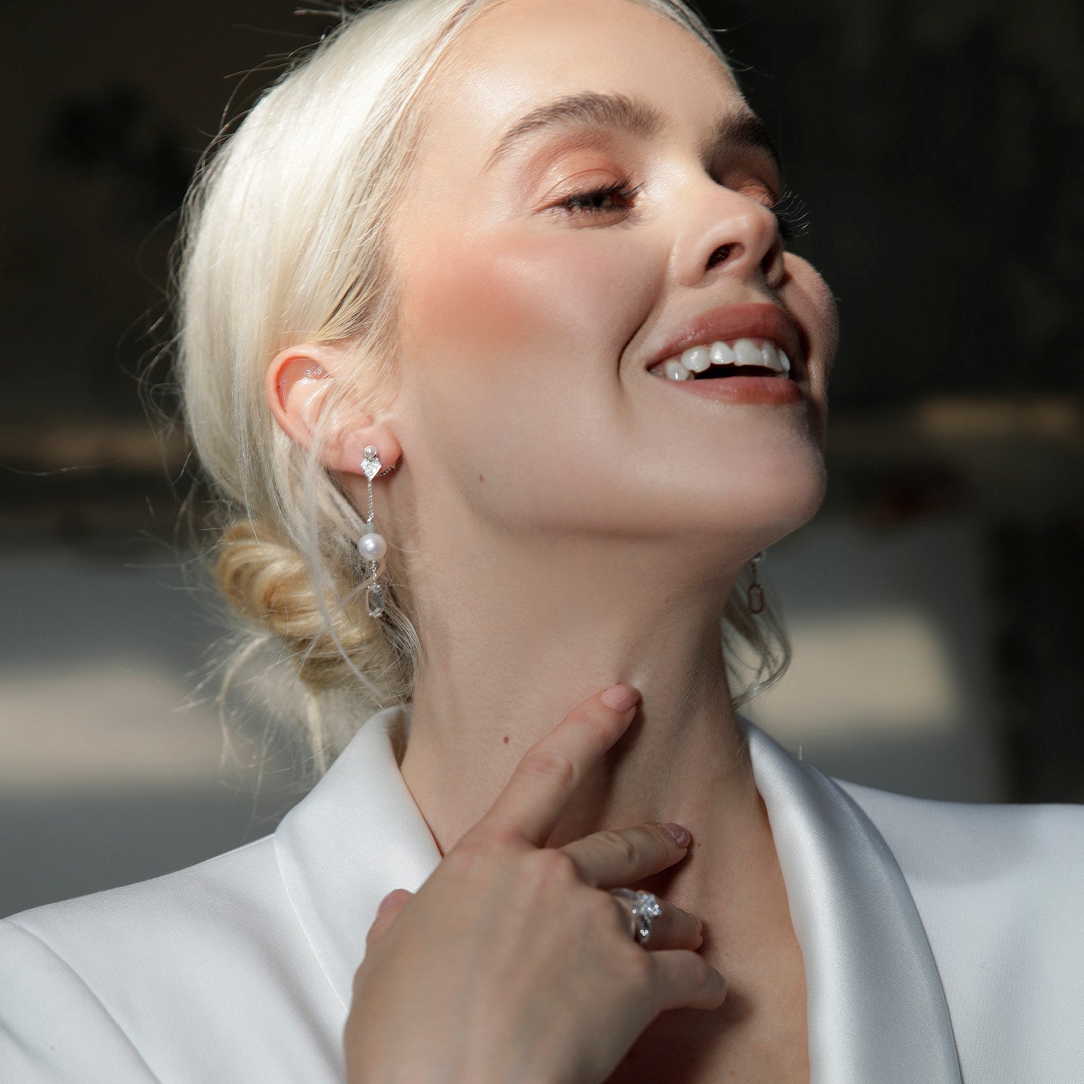 Blonde model wearing drop earrings featuring pearl, aquamarine, and clear quartz