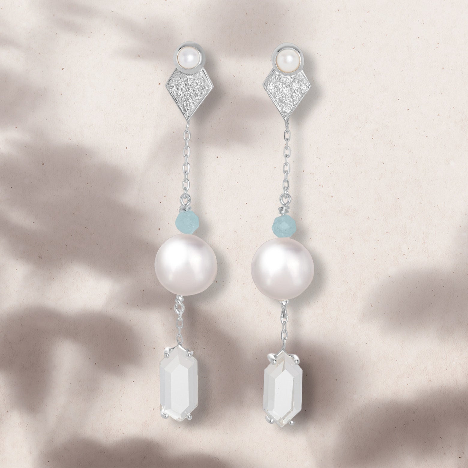 Flat lay of drop earrings featuring pearl, aquamarine, and clear quartz