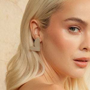 Close up of blonde model wearing asymmetric silver heart earrings