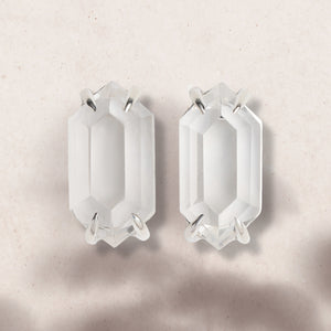 Flat lay of faceted clear quartz earrings in silver claw setting