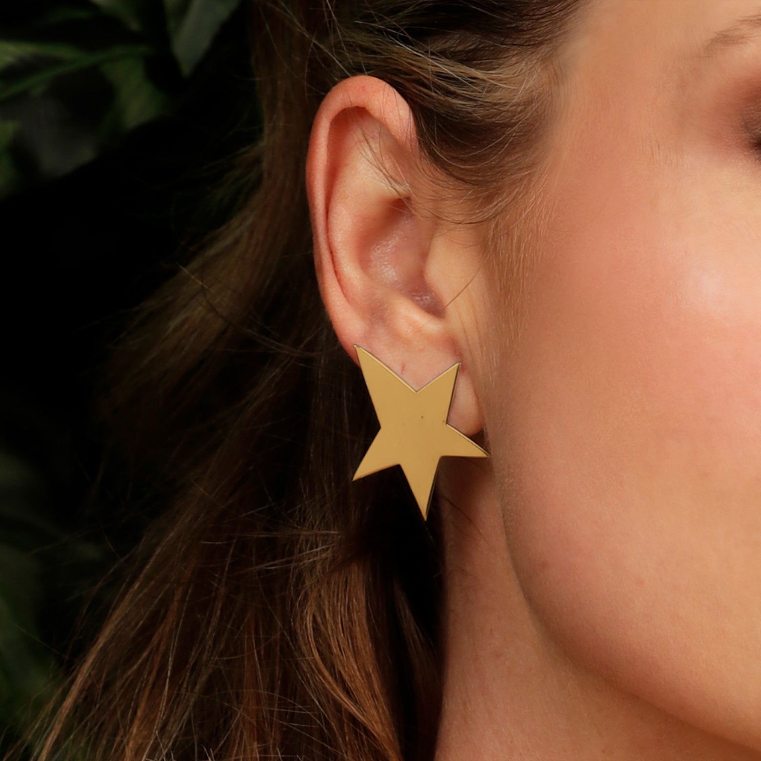 Close up of an ear wearing the Kelly Woodcroft gold starfish earrings.
